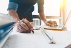 Image of engineer drawing a blue print design building or house, An engineer workplace with blueprints, pencil, protractor and safety helmet, Industry concept